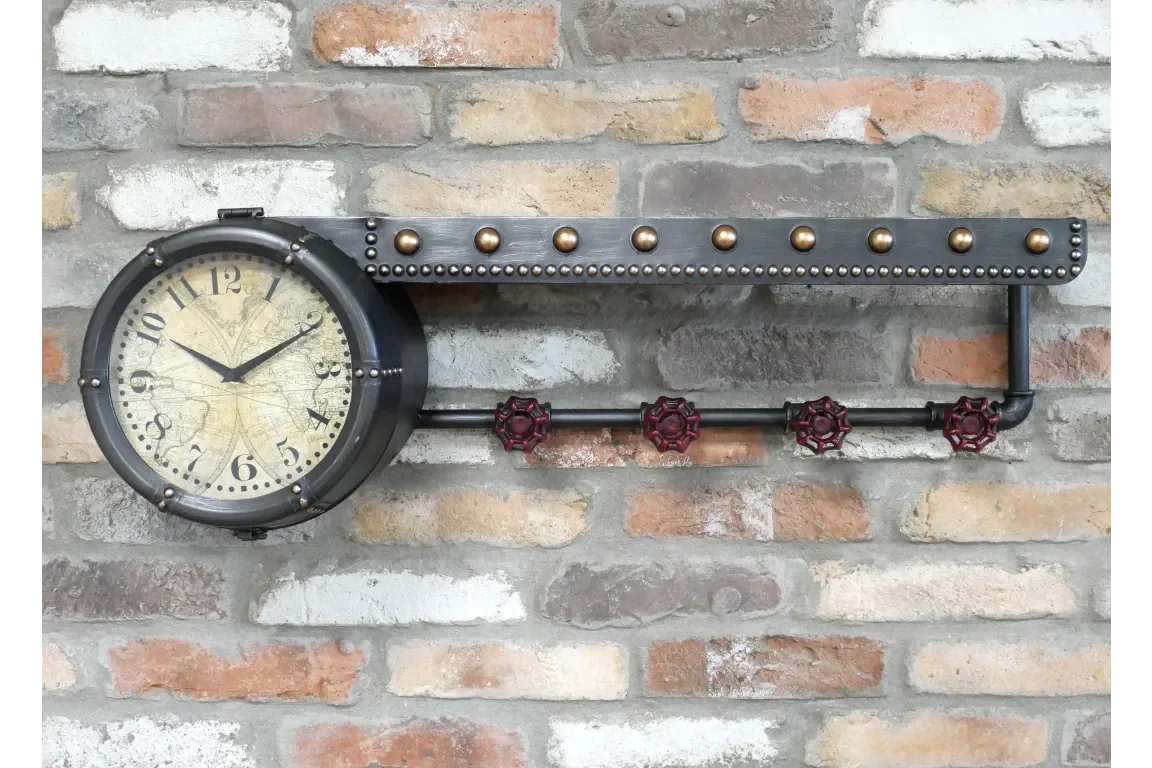 Industrial wall clock with metal frame and red valve accents on exposed brick wall