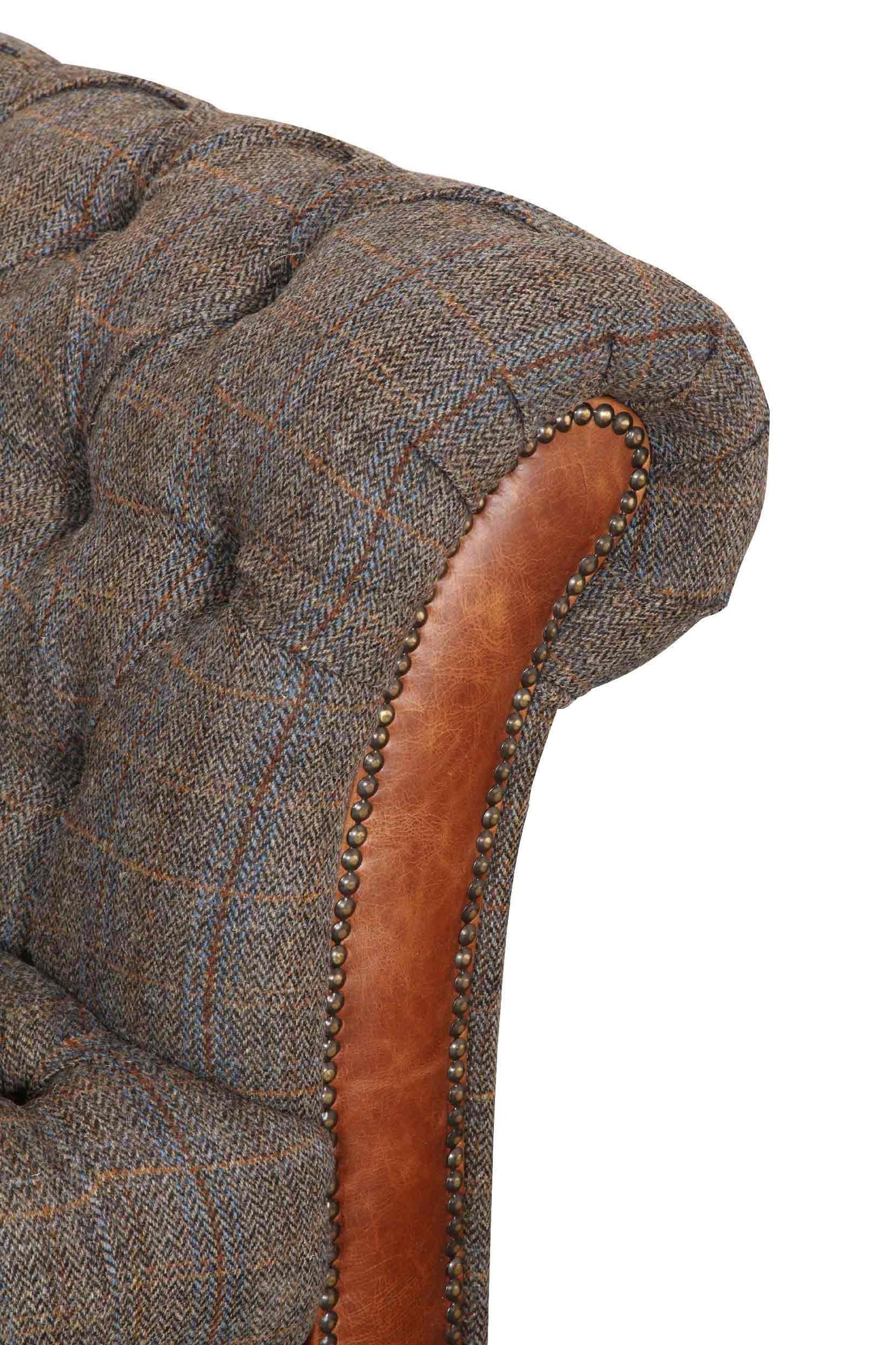 Close-up of tufted fabric and brown leather sofa arm with studded trim