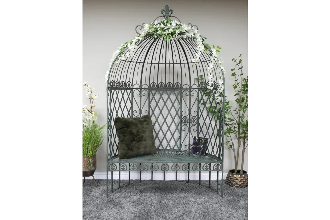 Metal garden arbour seat with floral garland, dark green cushion and book on grey rug