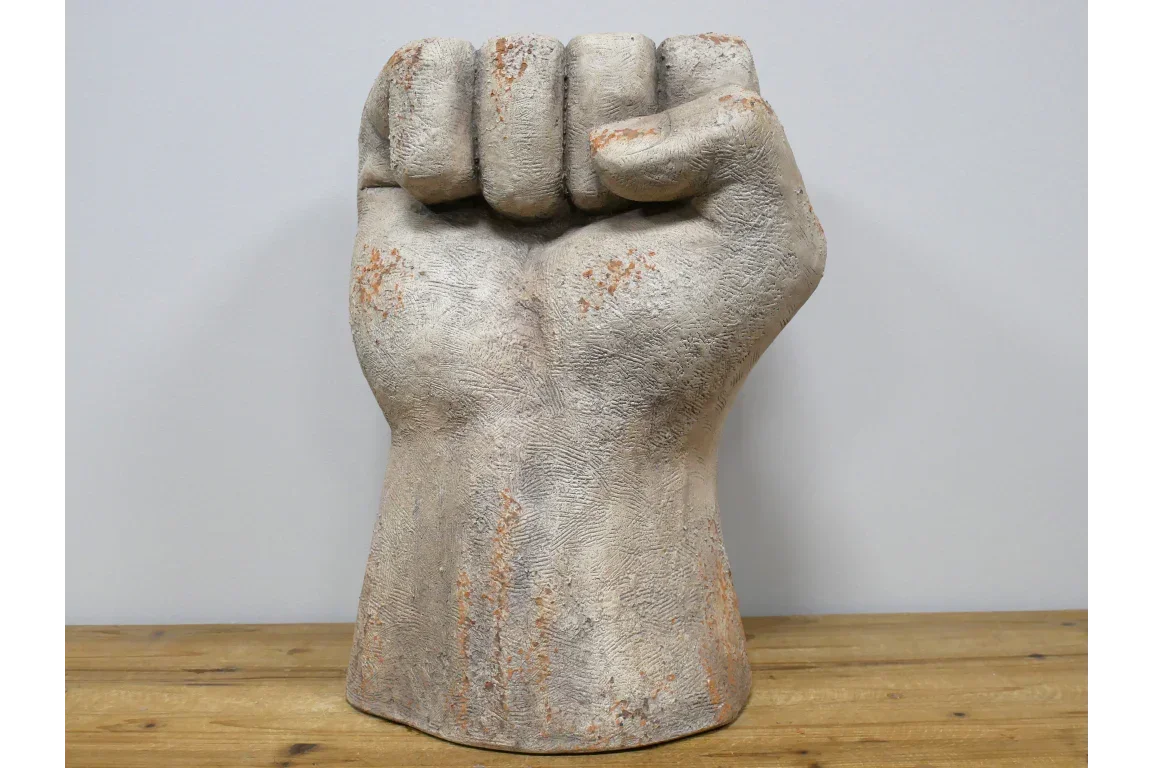 Stone effect hand sculpture shaped as a fist on wooden surface