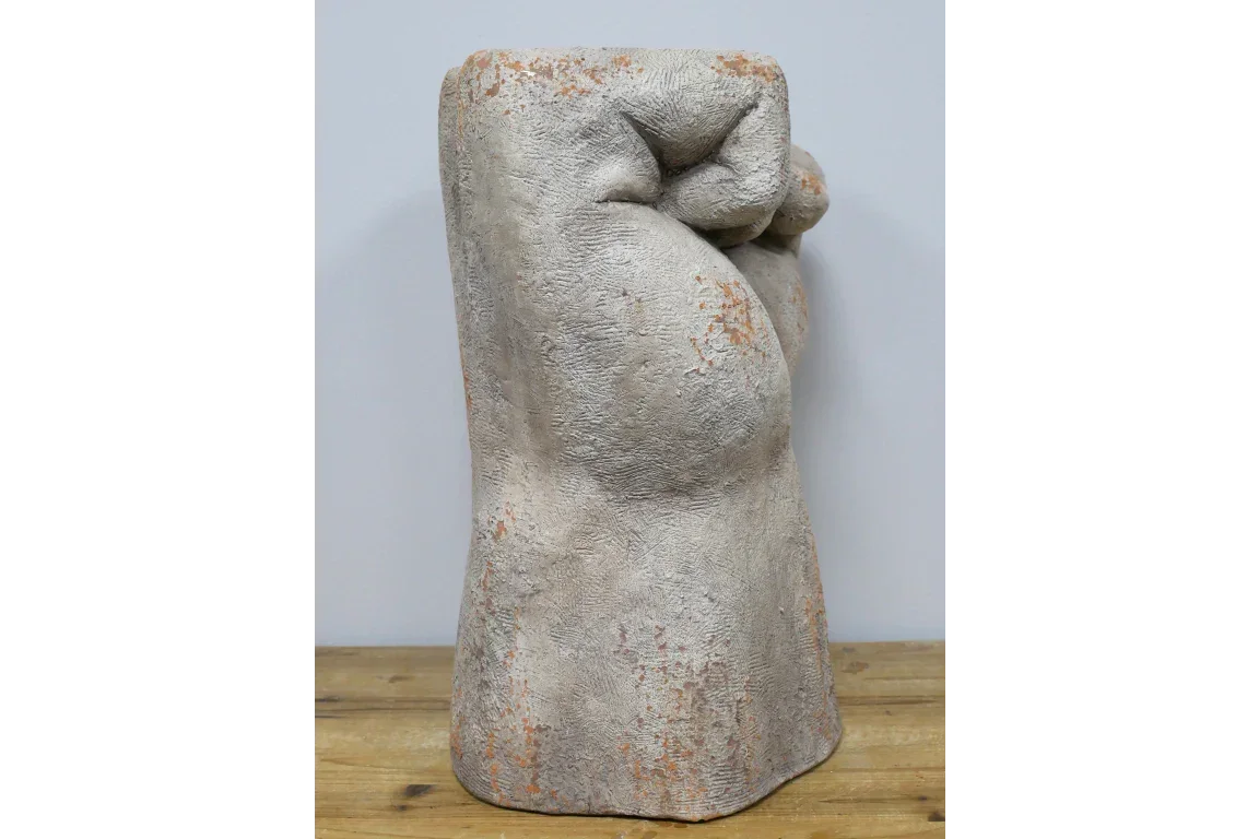 Concrete-effect decorative fist sculpture with textured surface on wooden tabletop