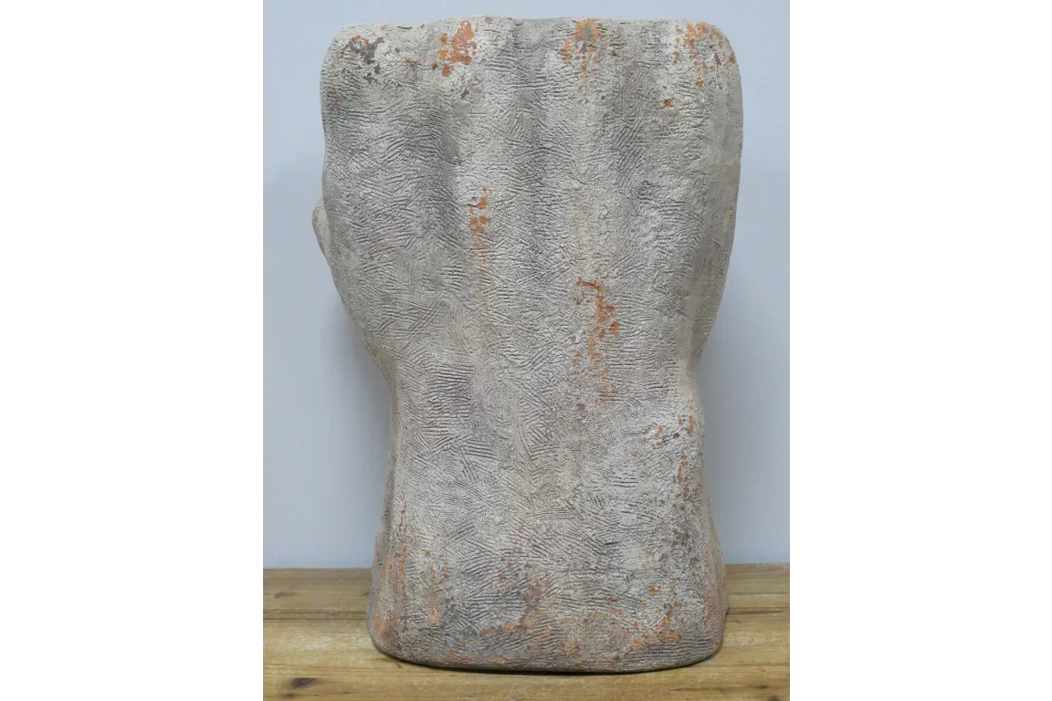 Textured stone effect ornament with a hand-shaped design on wooden surface
