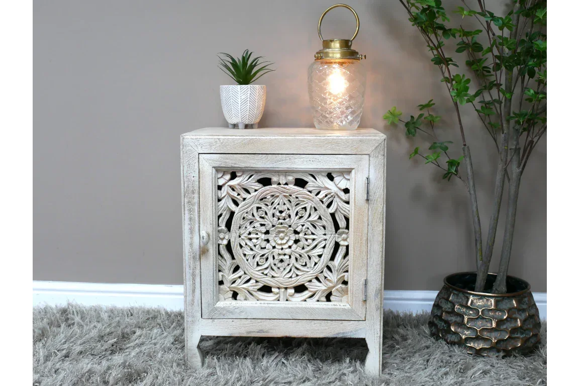 Carved wooden bedside cabinet with floral pattern, styled with lamp and plant on top