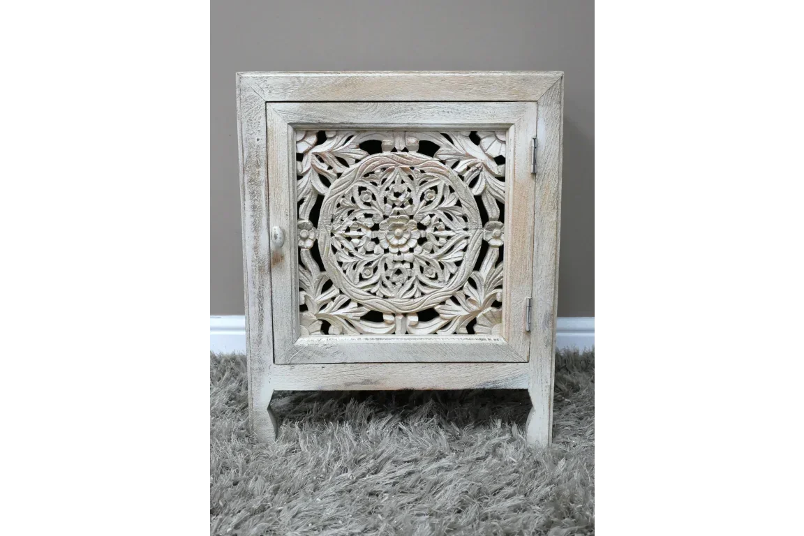 Carved wood bedside cabinet with floral pattern front panel on grey shag rug