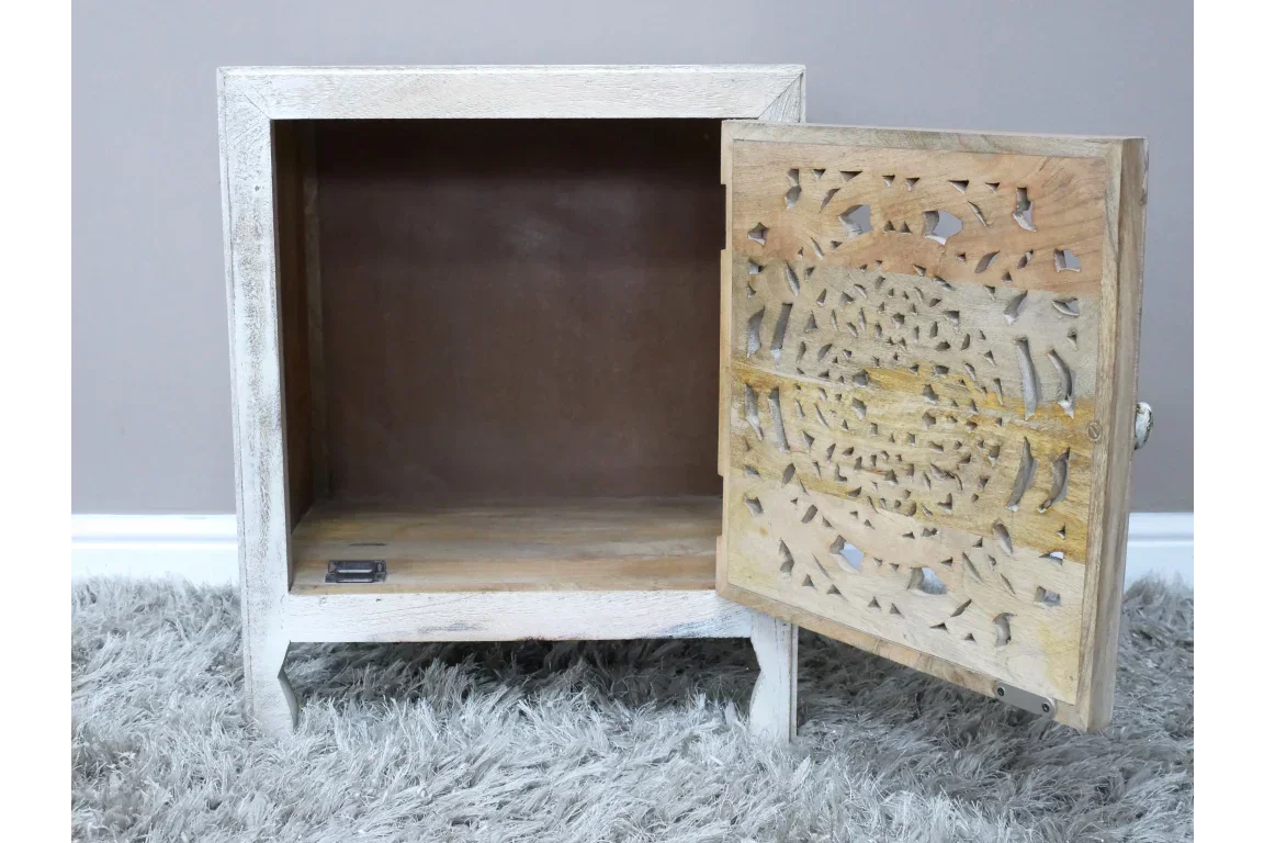 Wooden bedside cabinet with open carved door and light finish on grey rug