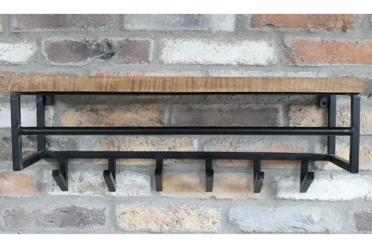 Industrial wall coat rack with black hooks and wood shelf mounted on brick wall