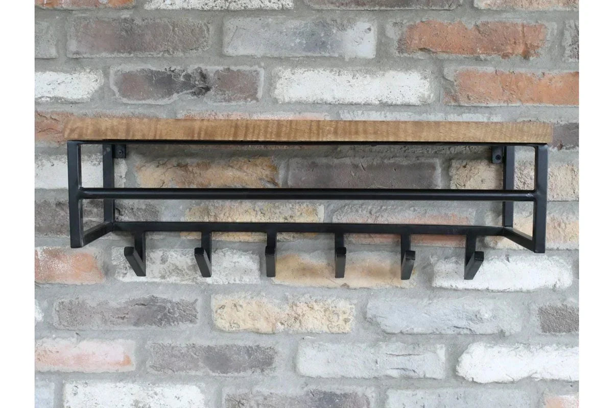 Industrial wall mounted coat rack with wooden shelf and five black hooks on brick wall