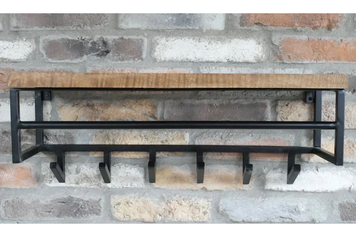 Wall mounted coat rack with wooden shelf and black metal hooks on exposed brick wall