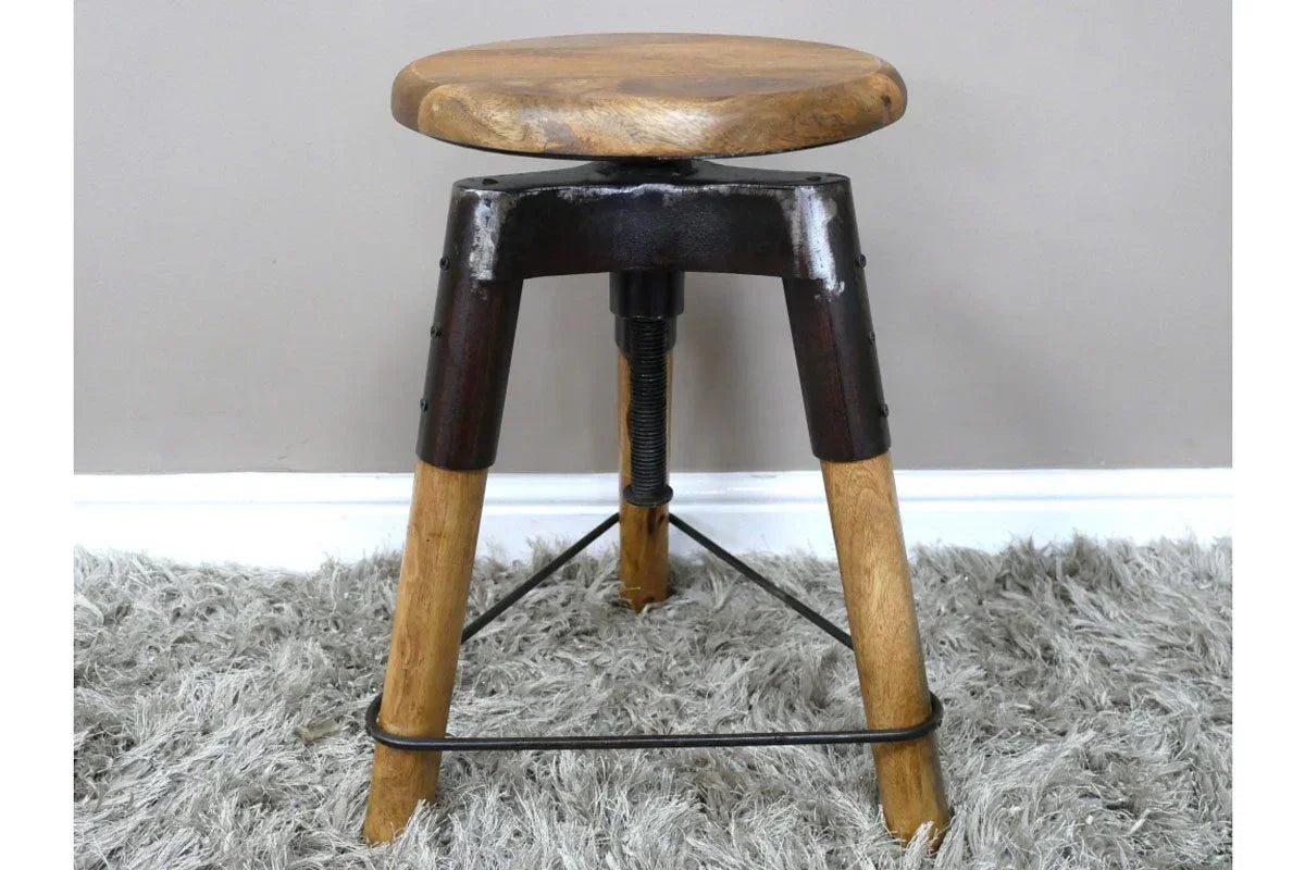 Industrial bar stool with round wooden seat and metal tripod legs on grey rug