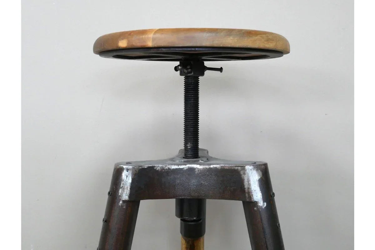 Industrial bar stool with round wood seat and metal tripod base, close-up side view