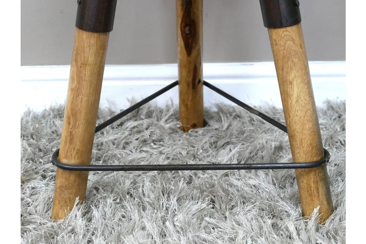 Close view of wooden dining table legs with metal supports on grey shaggy rug