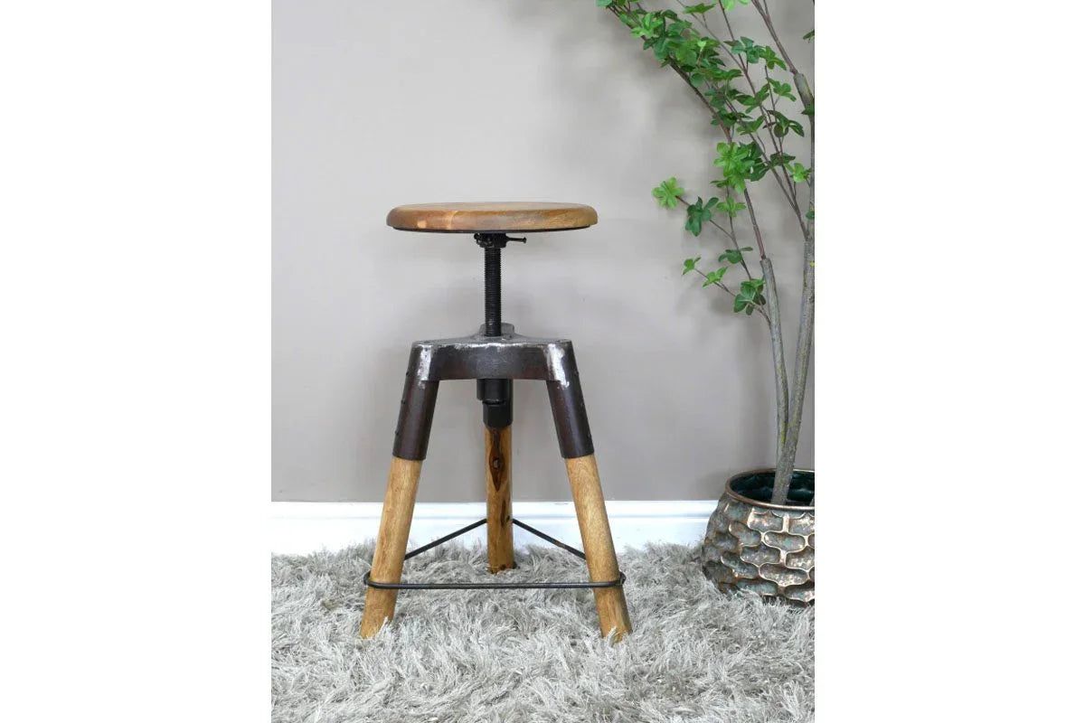 Industrial style bar stool with wooden seat and tripod legs on grey rug