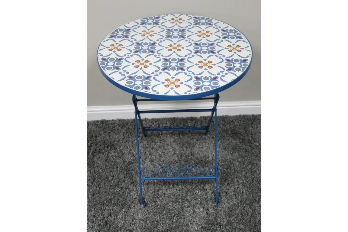 Round mosaic side table with blue and orange pattern and blue metal legs on grey carpet