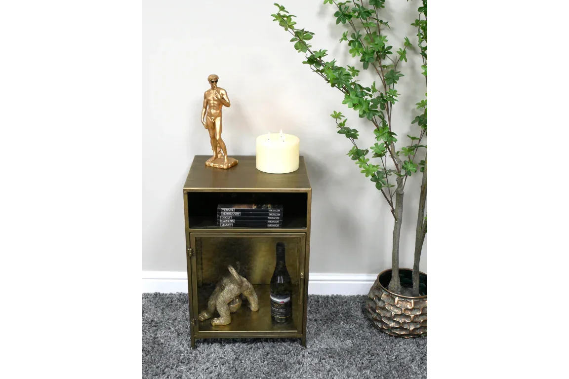 Brass metal side table with open shelf, stacked books, cabinet door, and decor accessories