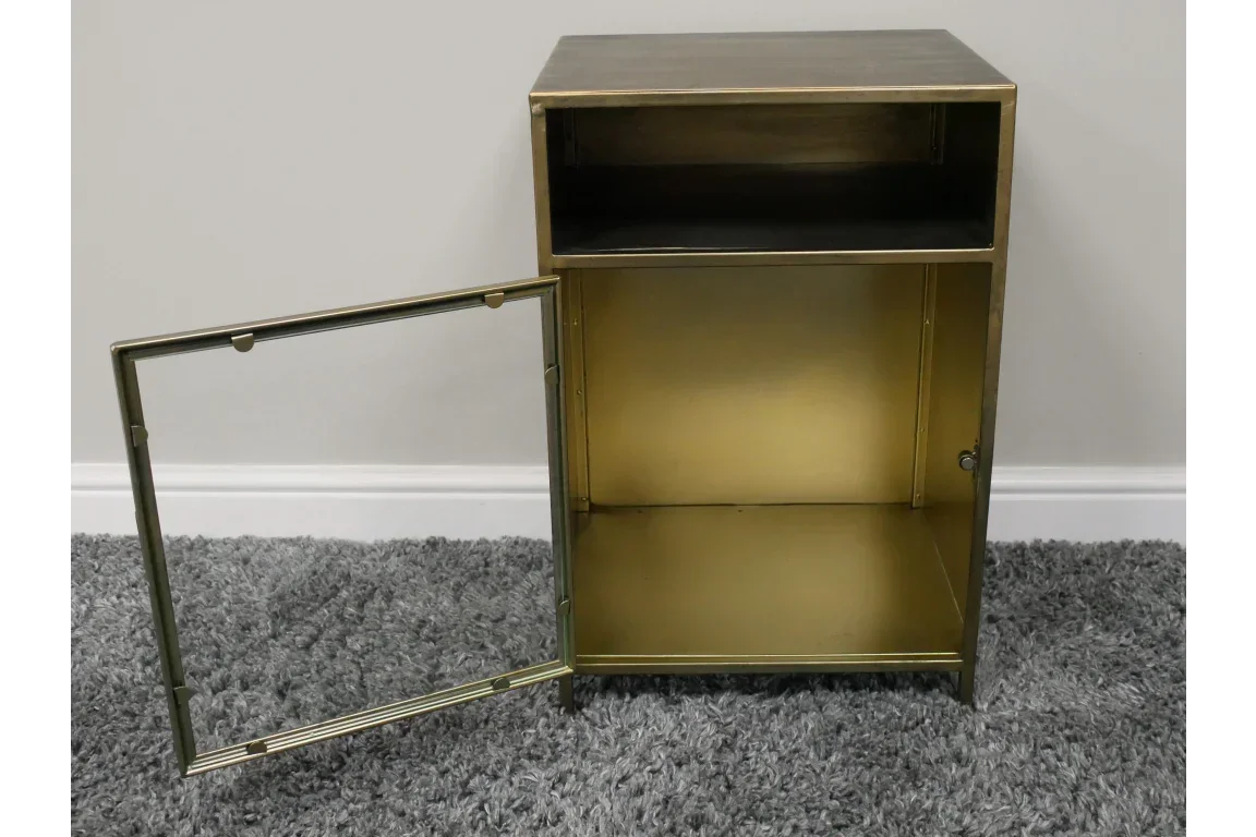 Brass metal bedside cabinet with open door, shelf compartment and gold finish on grey carpet
