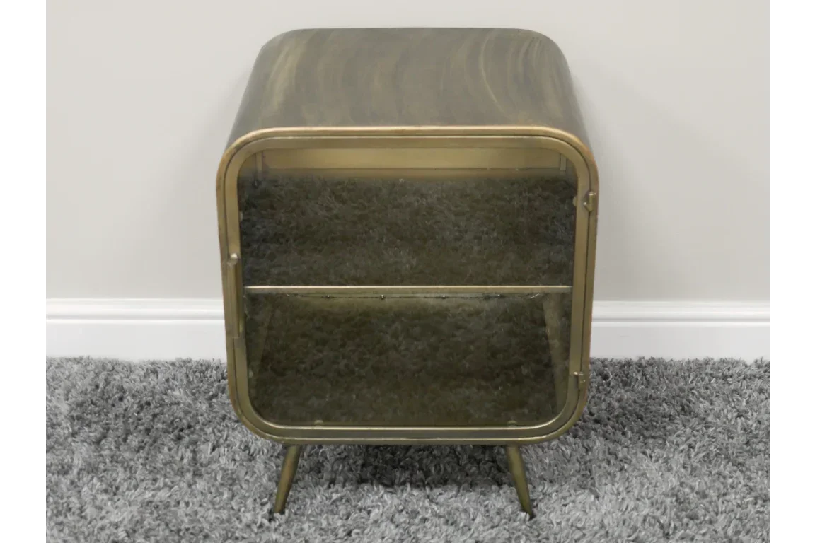 Brass metal side table with curved edges and glass door on grey carpet