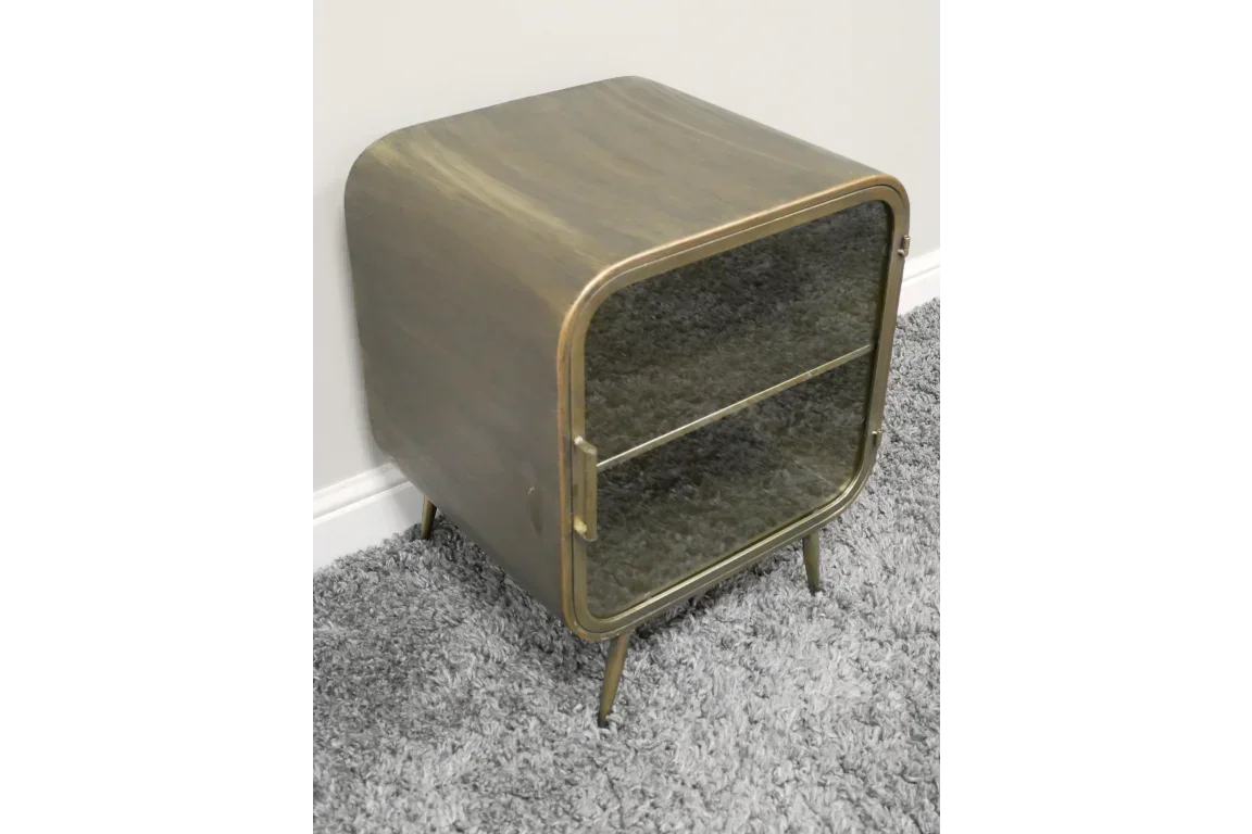 Brass metal bedside cabinet with glass door and shelf on gray carpet