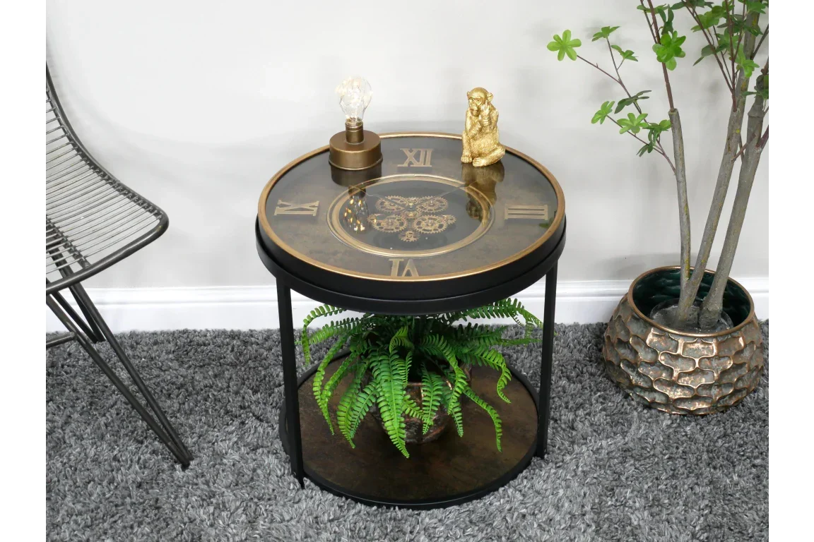 Round clock face side table with glass top, gold Roman numerals, and lower shelf with fern plant