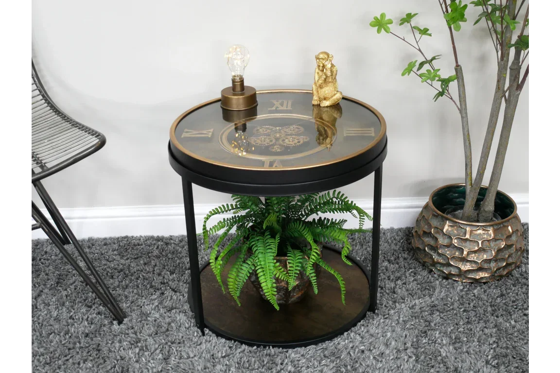 Round glass side table with Roman numeral clock face, black frame, and lower shelf with plant