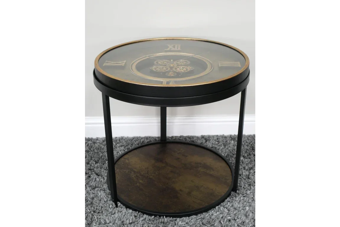 Round black metal side table with clock face glass top and lower wooden shelf on grey rug