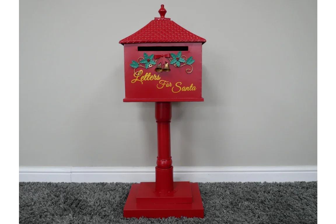 Red Christmas letterbox with Letters for Santa text and bells, on stand against wall