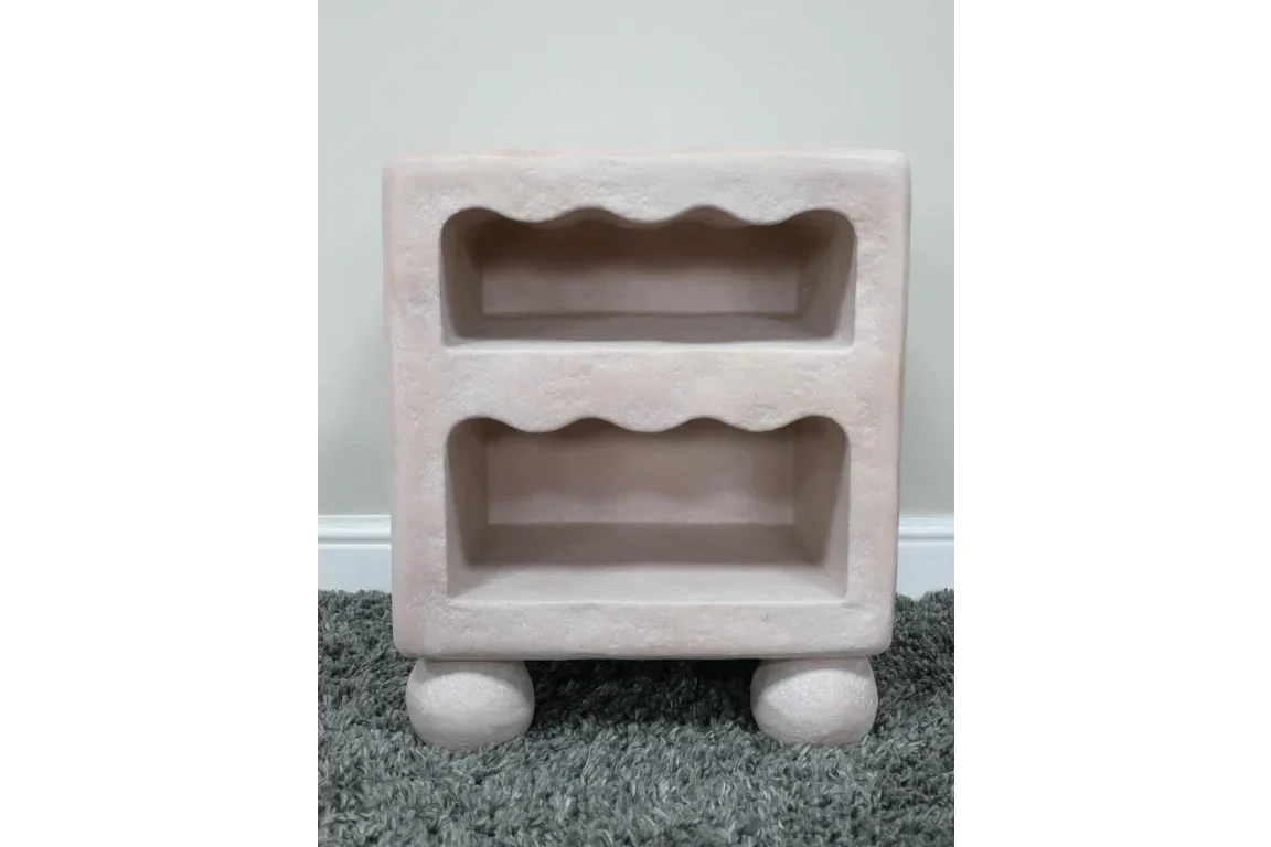 Stone finish bedside table with two open shelves and rounded feet on grey carpet