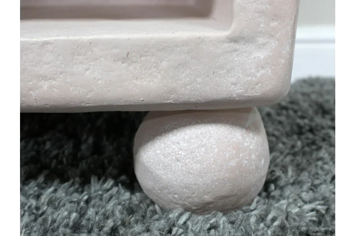 Stone furniture leg with rounded base on grey textured rug