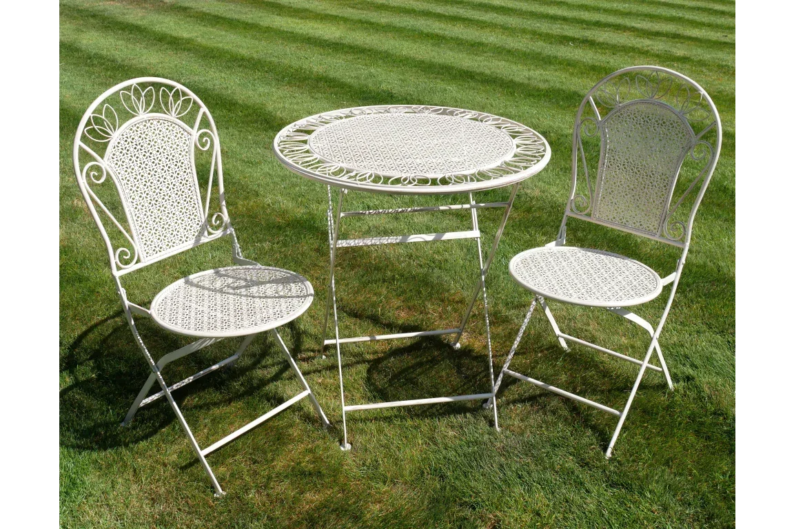 White metal bistro set with round table and two chairs on grass lawn