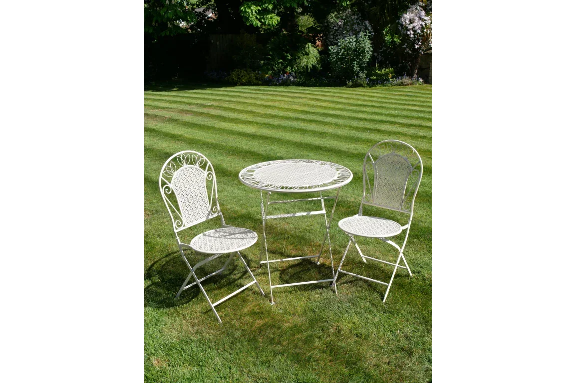White metal bistro garden furniture set with round table and two chairs on lawn