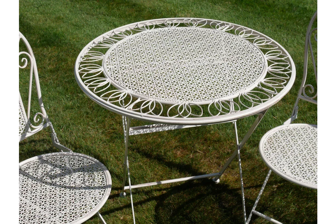White metal outdoor dining table and chairs with decorative cutout pattern on lawn