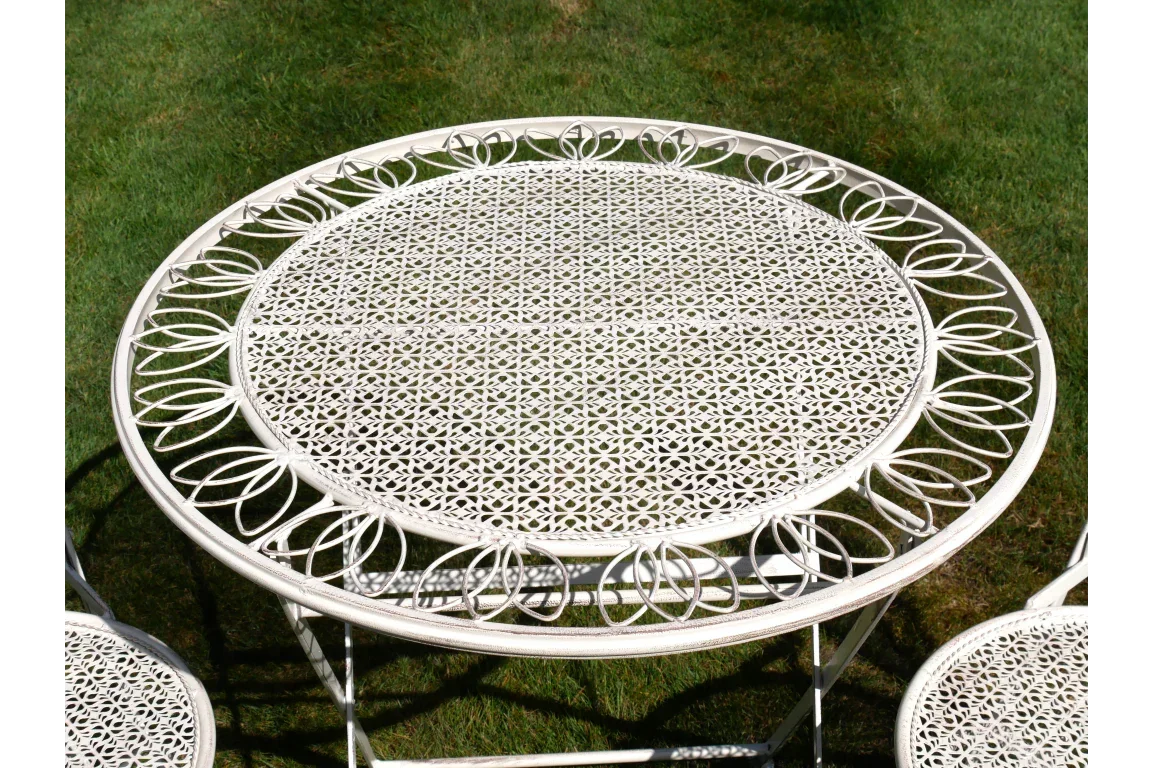Round white metal garden table with decorative cut-out pattern on grass