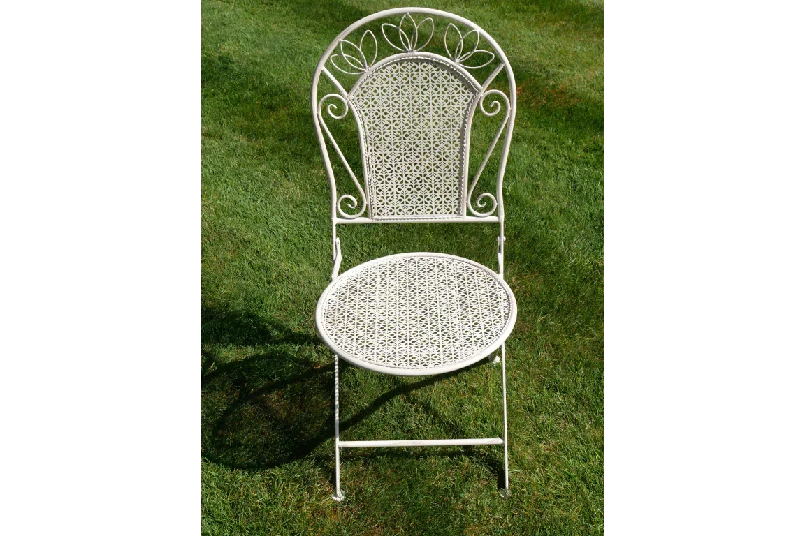 White metal garden chair with ornate backrest and round seat on lawn