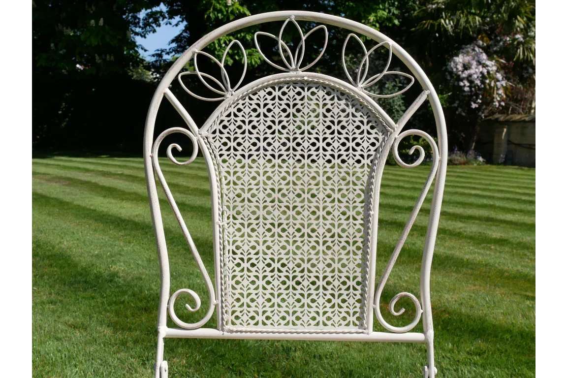 Cream metal garden chair with floral cutout backrest on lawn
