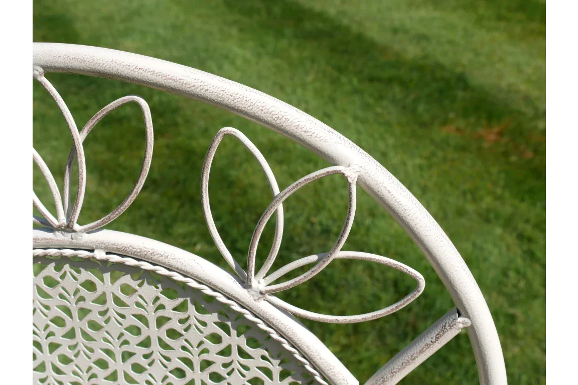 White metal garden bench with floral backrest detail on lawn