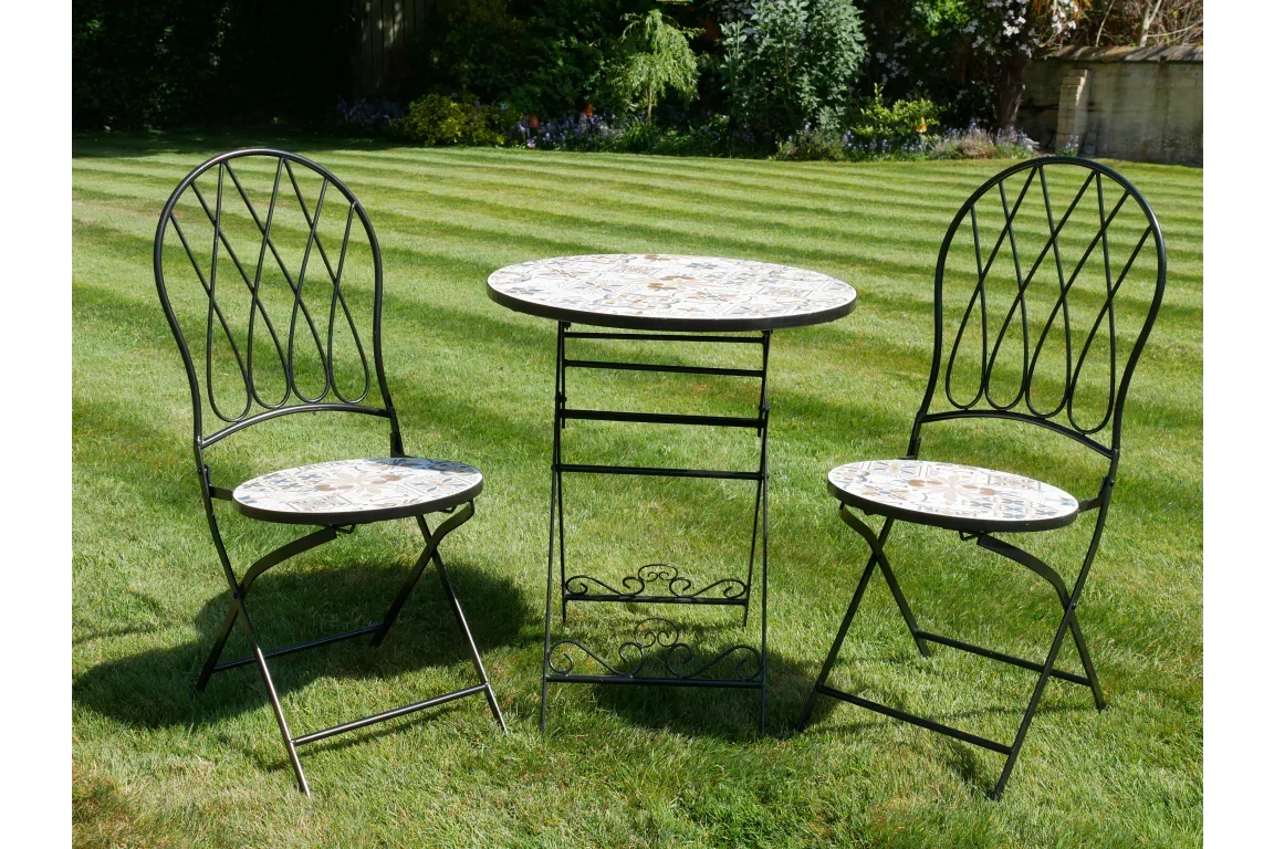 Mosaic bistro set with round table and two metal chairs on garden lawn