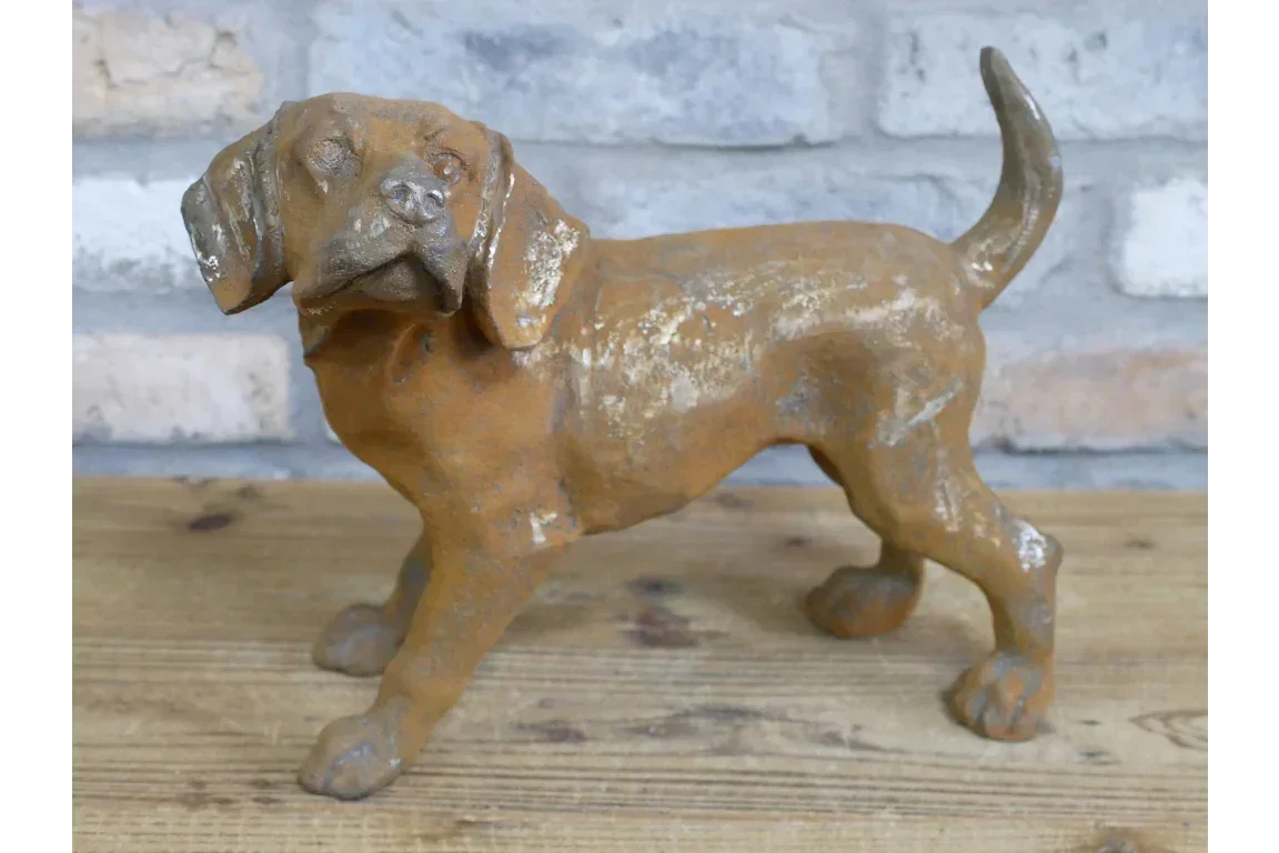 Rust finish cast iron dog ornament on wooden surface against a brick wall