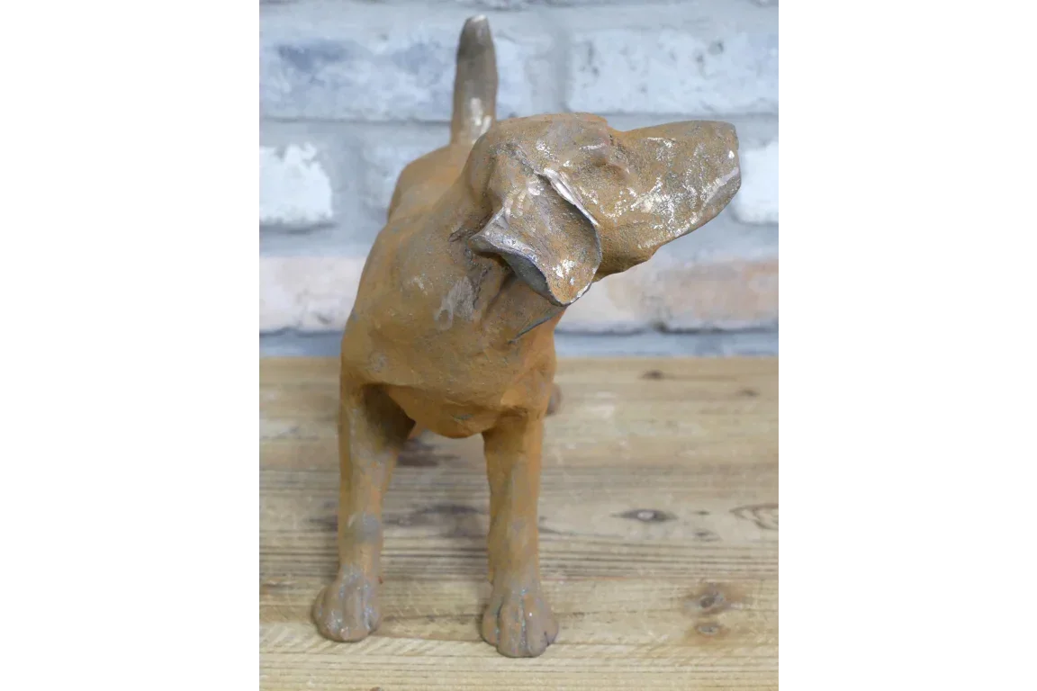 Brown dog sculpture ornament on wooden surface against a light brick wall backdrop
