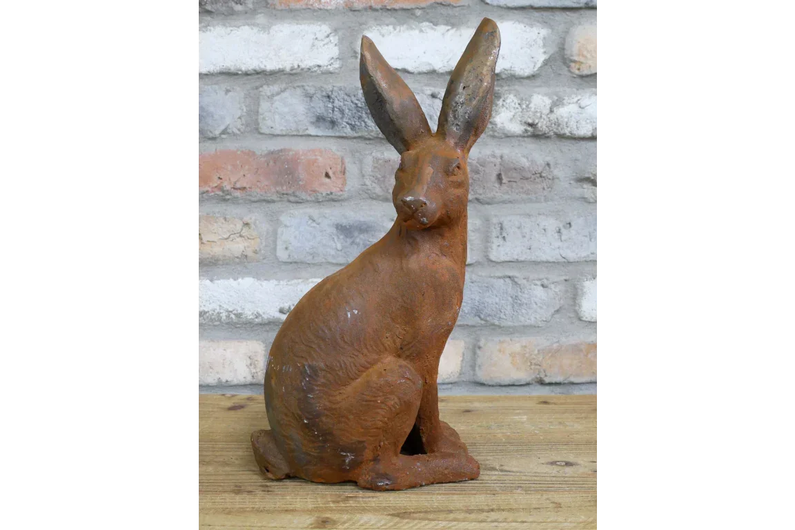 Rust effect hare garden ornament on wooden surface with brick background