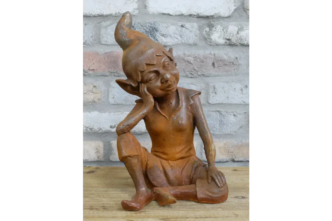 Rustic garden elf ornament seated on wooden surface with brick wall background