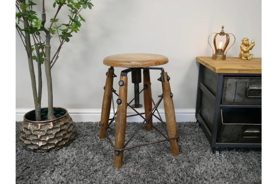 Industrial wood and metal stool with round seat on grey carpet beside metal side table