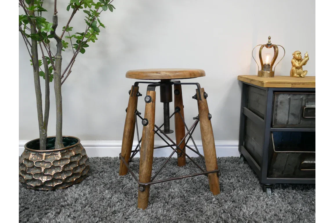 Industrial wooden bar stool with metal legs on grey rug beside cabinet and indoor plant