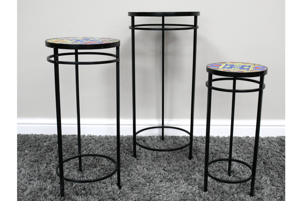Set of 3 black metal side tables with colorful mosaic tile tops, displayed on gray carpet against a white wall.