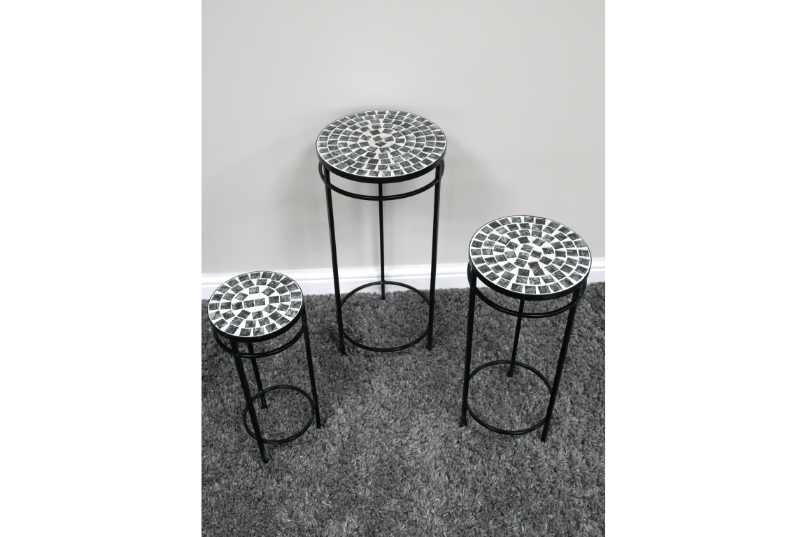Set of 3 round side tables with black metal frames and mosaic tile tops in black and white on gray carpet.