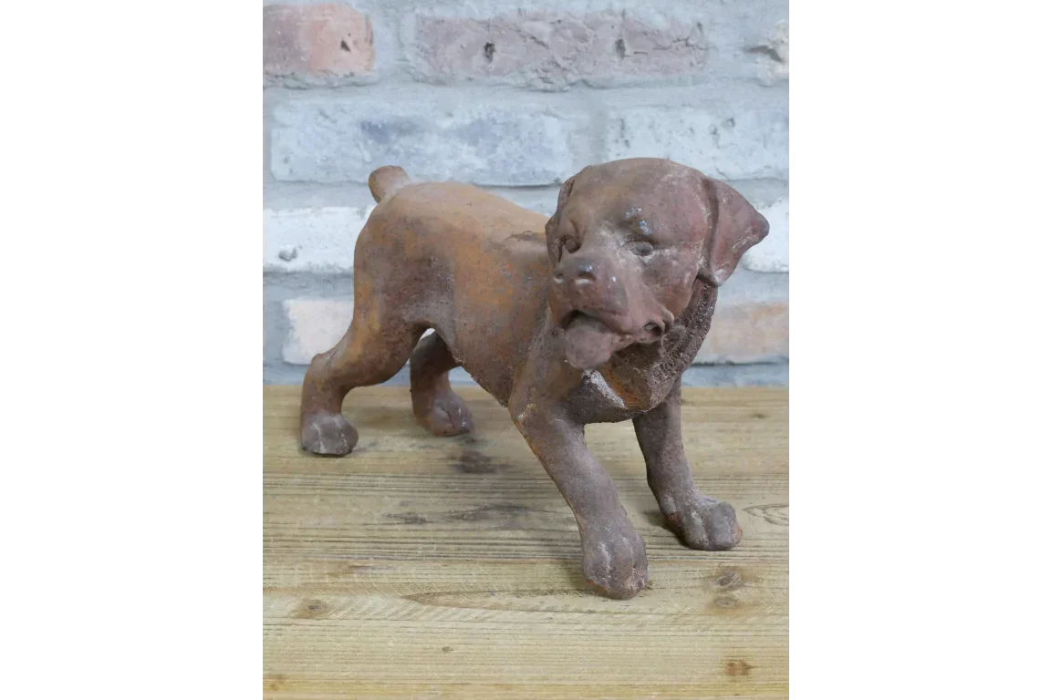 Rust effect cast iron dog ornament on wooden surface against brick wall