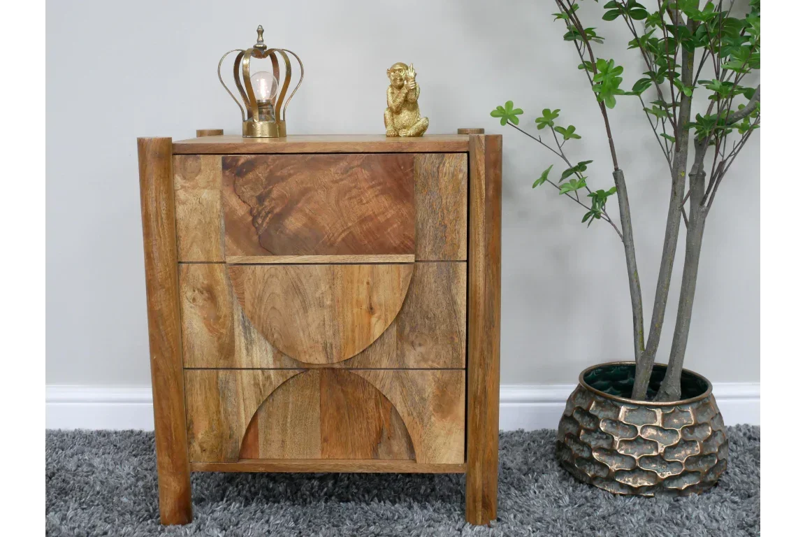 Solid wood bedside cabinet with geometric drawer fronts, gold decor, and indoor plant