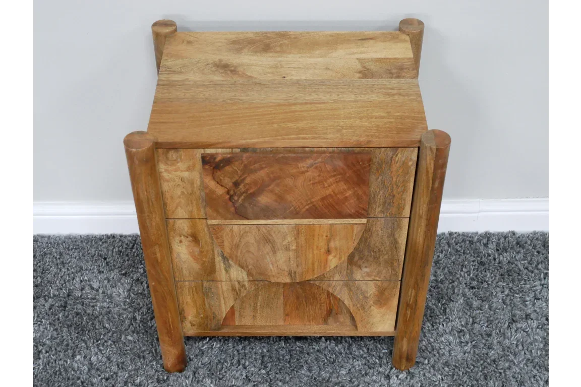 Solid wood bedside table with three drawers and geometric carved front on grey carpet
