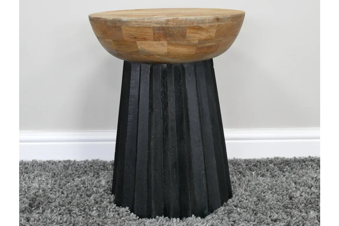 Round wood and black side table with fluted base on grey carpet