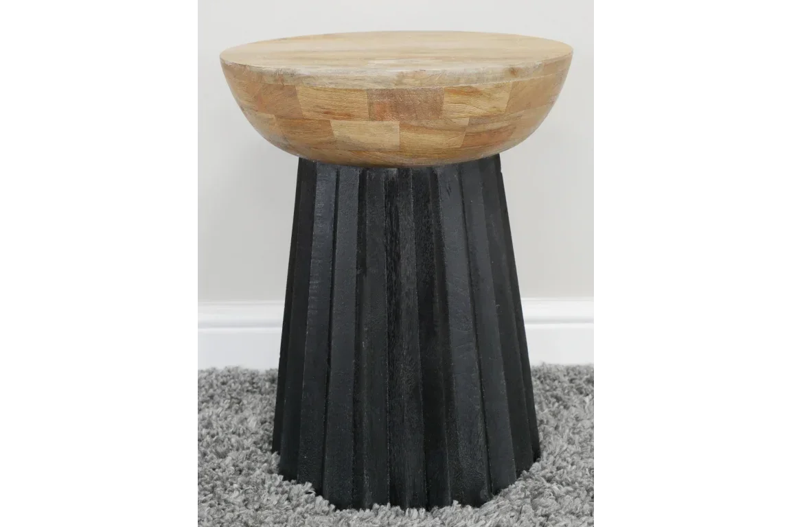 Round wooden side table with natural top and black fluted base on grey carpet