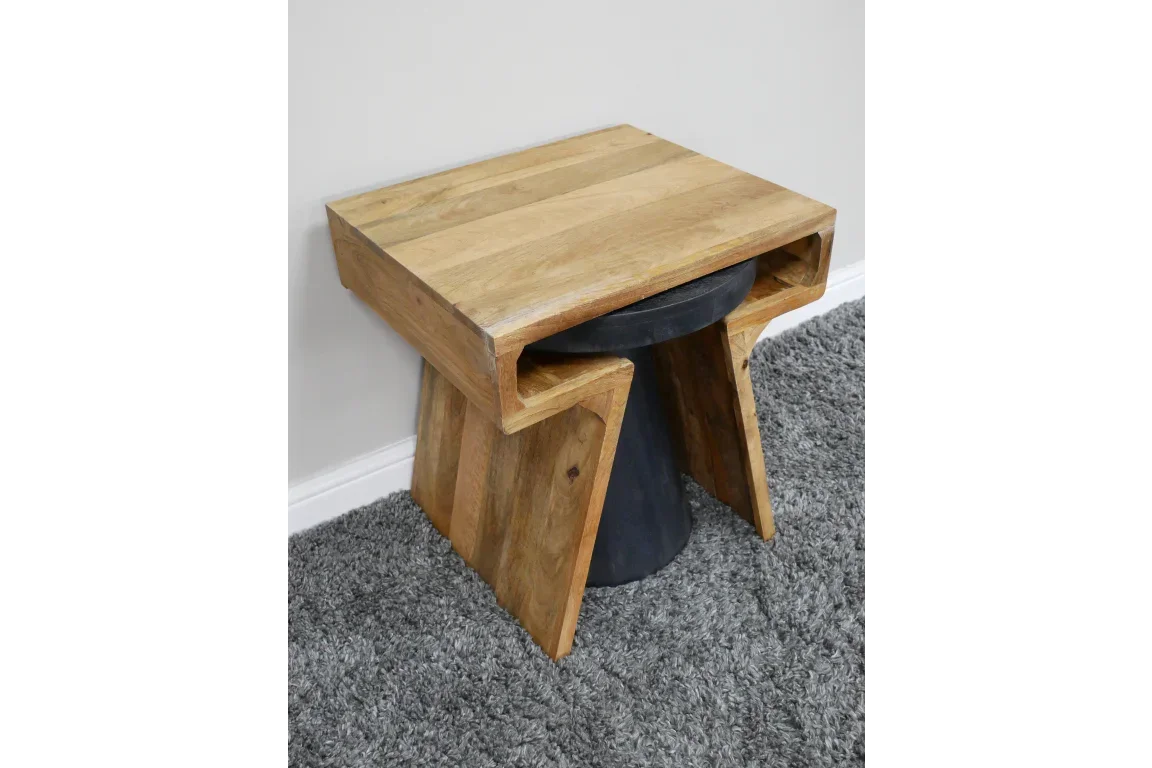 Wooden side table with angled legs and black accent base on grey carpet