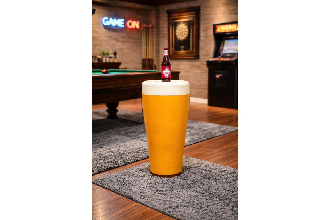 Round yellow Lager Side Table resembling a pint glass with white top, set on a grey rug in a game room.